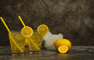 Fresh lemon juice with ice with fresh lemons on a gray background. Lemonade with fresh lemons on a gray background. Fresh juice lemonade.