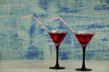 Red cocktail with pomegranate juice in a martini glass with ice on a gray background. Red cocktail with martini and pomegranate juice on a gray stone background.