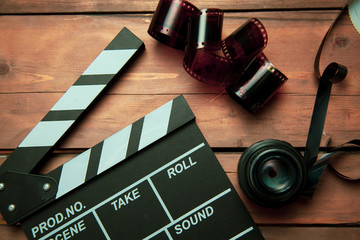 Movie clapper, filmstrip and lenses on wooden background