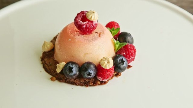 top view closeup pink icing dessert with bize and berries rotates on plate