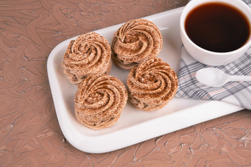 Food, dessert, handmade marshmallows. On a white plate are delicious, sprinkled with cinnamon and chocolate four marshmallows, a Cup of tea and a variety of marmalade.