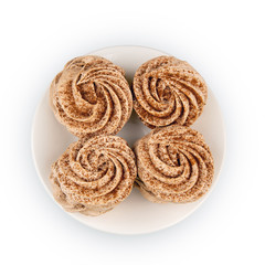 Four marshmallows, sprinkled with cinnamon and chocolate, lie on a white plate. Top view, isolated on a white background.