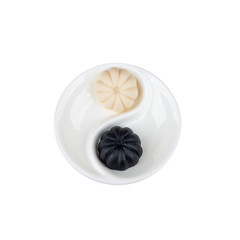 Natural fruit and milk marmalade Yin-Yang has a rounded shape and lies on a white menazhnitsa, divided among themselves. Selection on a white background.
