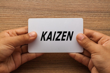 Kaizen or Continuous improvement written on white card holding with two hands