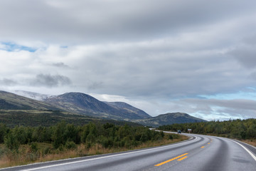 Mountains in Norway road epic scenic sky, way, clouds view. Traveling by car, driving nature tourism. Dramatic skyscape northern scandinavian sky