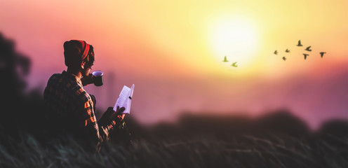 a young boy read the book behind background sunset and birds flying.