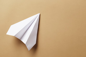 Flat lay of white paper airplane and blank paper on  background.