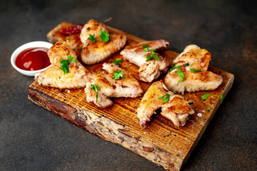 grilled chicken wings on a cutting board with spices and herbs on a stone background