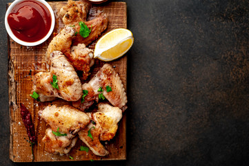 grilled chicken wings on a cutting board with spices and herbs on a stone background