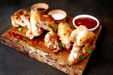 grilled chicken wings on a cutting board with spices and herbs on a stone background
