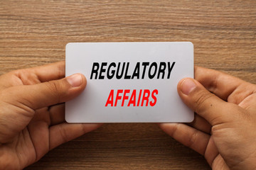 Regulatory Affairs written on white card holding with two hands
