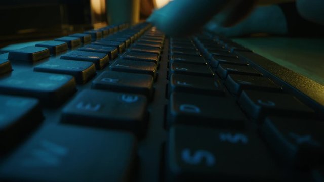 Close-up Moving Macro Shot: Person Typing on the Computer Keyboard finishing with Pressing Enter Button. Working, Writing Emails, Using Internet. Dark and Blue Colors