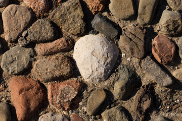 Background of colored stones. The surface is decorated with natural material. Pattern on the floor of multicolored pebbles.