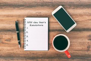 New year Concept - 2020 number and text on notepad. Smartphone, pen and cup of coffee background.
