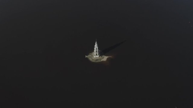 Aerial footage of flooded Kalyazin Bell Tower in Uglich Reservoir on the Volga River. Boat sailing to the tower. Kalyazin, Russia. Kalyazin from drone.