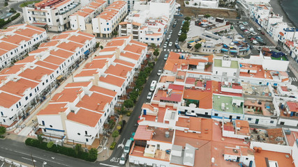 Fototapeta na wymiar Aerial view. Tiled roofs of white resort houses off the coast of the Atlantic. The coastal city of Agaete, Gran Canaria.