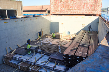 Vejle/Denmark - 05.16.2019 : discharging of steel product in cargo port from holds of cargo vessel. Cargo delivered from Finland to Denmark. Old age stevedores are working in cargo hold