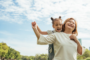 Nice little girl run to grandmother's hug in park.Grandmother and grand daughter enjoying sunny...