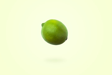 Fresh lime levitate in air over yellow background. Concept of fruit levitation.