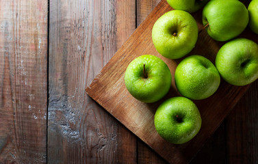 Juicy green organic apples and drops of water on a wooden background. Healthy food.