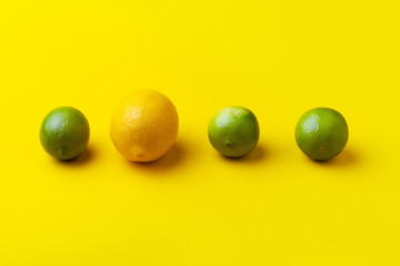 three limes and one lemon on a yellow background, concept of a unique, unusual idea