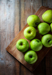 Juicy green organic apples and drops of water on a wooden background. Healthy food.