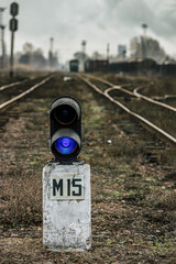 Railway traffic light with a blue standard signal. Semaphore on railroad crossing on a blurred...
