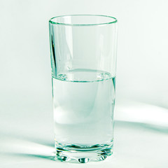 Pure clear water in a glass glass and glass jug stands on a white background