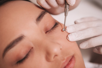 Cropped clsoe up of a beautician removing blackheads on cheeks of a female client