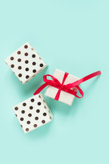 Christmas flat lay on top, New Year gift in a box with a red ribbon on a neo mint background, festive decor, copy space