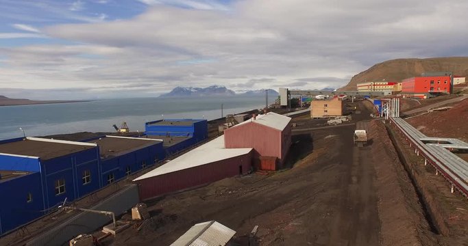 A truck moves along the road in Barentsburg, the Russian coal mining settlement. Second largest settlement on the Svalbard archipelago. The Arctic oceanscape is seen behind. Aerial view. 4K