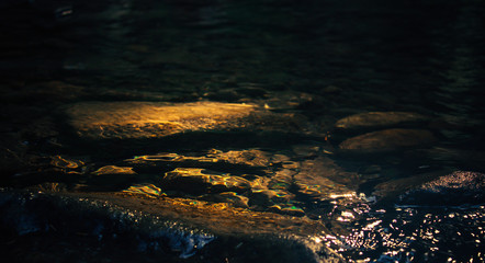 Quiet river with stones, reflection of the sun in the water