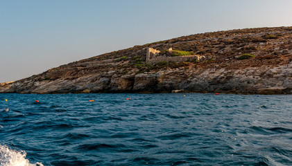 Fototapeta na wymiar Rocky island in the Mediterranean sea, shot from the boat level.
