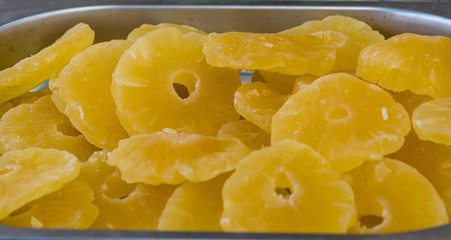 Sweet slices of fruit in a warm yellow color under a bright sun on a market stall.