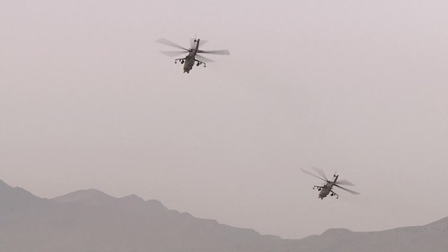 Combat link military helicopters flying over the desert between the mountains, attacking from the air of the enemy.