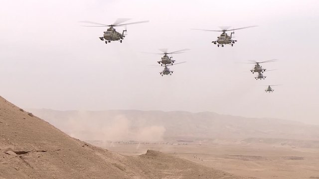 Combat link military helicopters flying over the desert between the mountains, attacking from the air of the enemy.