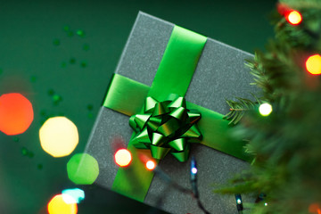 Christmas present with green ribbon under the Christmas tree.