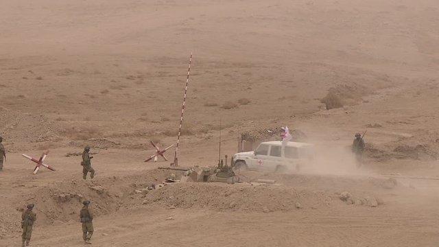 Cars with the red cross pass through a military checkpoint, a combat operation in the desert Sands.