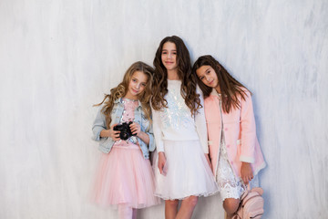Fototapeta na wymiar three beautiful fun fashionable girls in white pink dresses with a camera