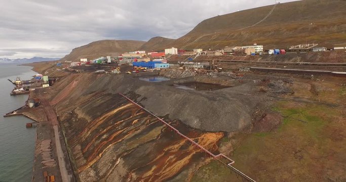 Spitsbergen. Aerial view over the coastline of Arctic ocean with the mining settlement on it. The industrial part of the town of Barentsburg stands on the hillside surrounded with arctic landscape.4K
