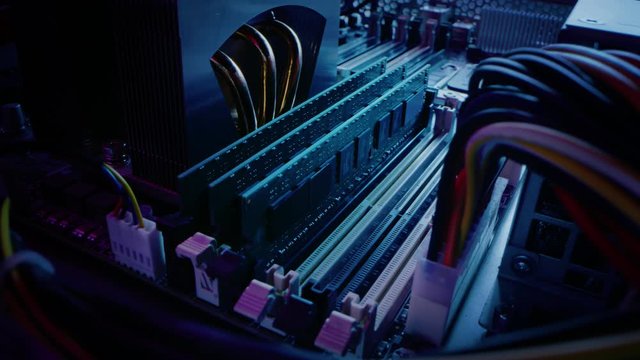 Close-up Moving Macro Shot: Person's Hands Installs RAM Memory into Computer Motherboard Slot. Technician Upgrades PC / Server System. Modern High-End PC Shot in Stylish Neon, Pink-Blue Colors. 