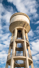 Old water tower. Vertical panoramic image. Clouds and dramatic sky in background.
