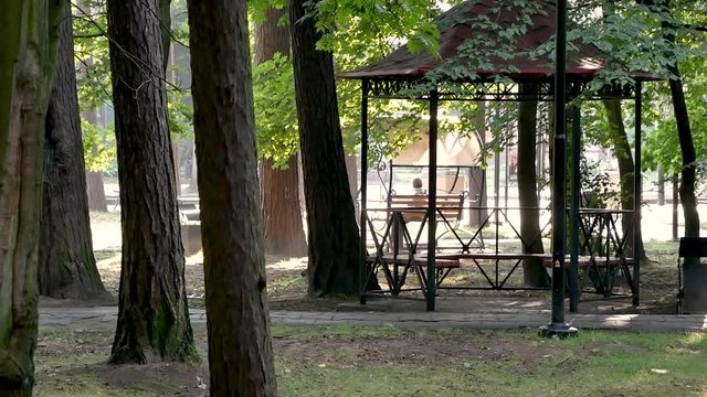 A woman sits on a swing in the parc of town