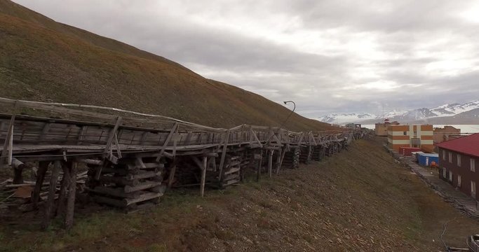 Drone aerial following the long technical pipe stretching by the ground along the coal mining settlement of Barentsburg, located on the coast of the Arctic Ocean in Spitsbergen. 4K