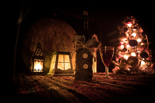 Red wine in crystal glass with bottle on colorful carpet with creative New Year artwork decorations. Copy space