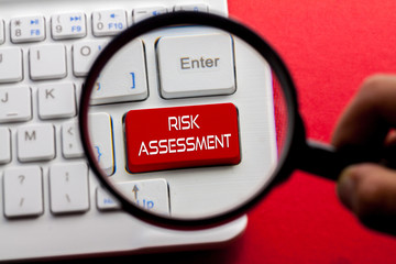 RISK ASSESSMENT word written on keyboard view with magnifier glass