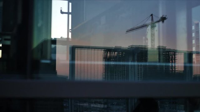 Silhouetted crane and buildings in downtown Denver reflected off a glass elevator at sundown