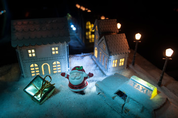 New Year miniature house in the snow at night with fir tree. Holiday concept. Selective focus