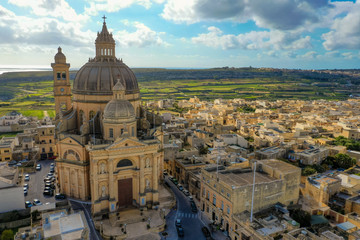 Obraz premium Aerial view oа St. John Baptist Church. Countryside of Gozo island, cloudy blue sky. Malta country