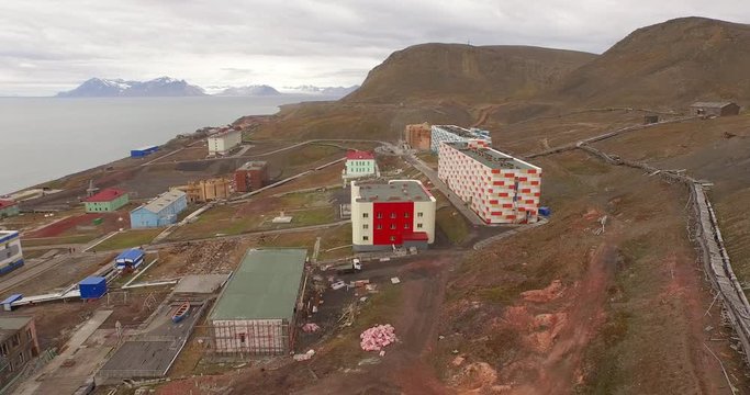 Drone aerial following the long technical pipe stretching by the ground along the coal mining settlement of Barentsburg, located on the coast of the Arctic Ocean in Spitsbergen. 4K